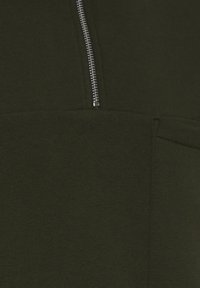 Mørkegrønt sweatshirt-stof med en glat tekstur, der har en sølvfarvet lynlås og en lomme-detalje på forsiden.