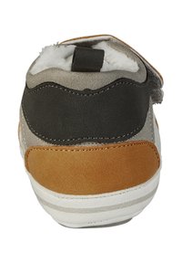 Rückansicht eines Schuhs mit einer Mischung aus grauem, schwarzem und braunem Wildleder, einer weißen Gummisohle und einer Zuglasche am oberen Ende.