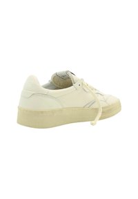 Sneaker bianca in pelle con superficie testurizzata, suola in gomma beige piatta e design minimalista. Presenta cuciture tonali e chiusura con lacci.