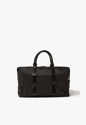 Schwarze Duffle-Tasche aus strukturiertem Stoff mit Ledergriffen, Reißverschluss und kontrastierenden, glänzenden Akzenten. Einfaches rechteckiges Design.