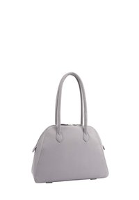 Lichtgrijze leren handtas met dubbele ronde handvatten en een bovenste ritsluiting, gestructureerde trapeziumvorm, rustend op kleine metalen voetjes.