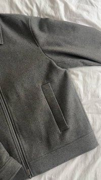 Gray wool jacket with a zip closure, side pocket, and a smooth texture. Features a simple design and tailored fit.