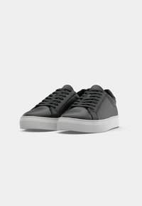 Black leather sneakers with smooth surface, rounded toe, white rubber sole, and flat laces. Simple design with no visible patterns or accents.