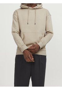 Sudadera beige con bolsillo delantero, capucha con cordón, puños y dobladillo de canalé. Tejido suave con un corte relajado, que combina con pantalones oscuros.