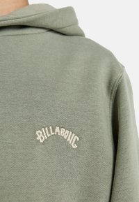 Felpa in cotone verde con finitura testurizzata, dotata di logo ricamato "BILLABONG" in bianco sopra la zona della spalla.