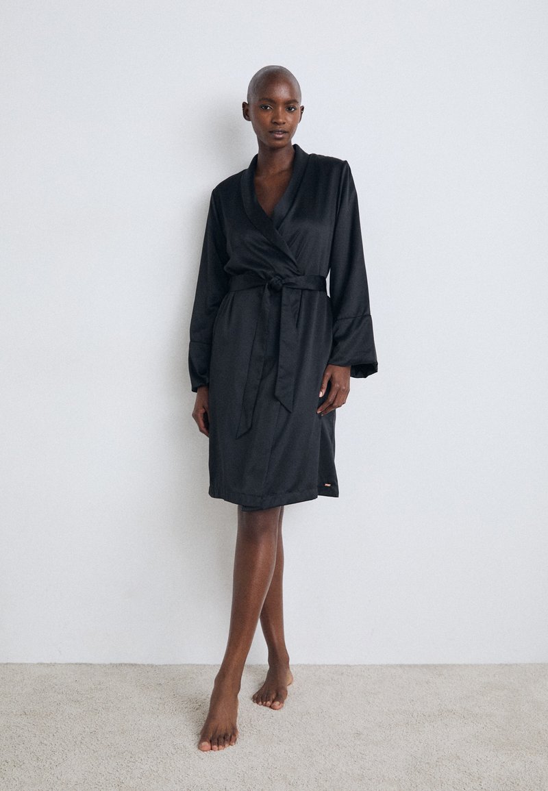 Svart satinbadrock med omslagdesign, långa ärmar och bälte. Slät textur och knälång klippning med en sidorslits.