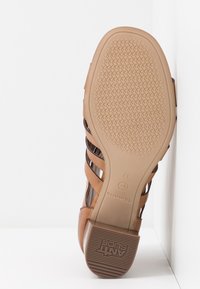 Semelle d'une sandale couleur cognac taille 37 avec talon texturé antidérapant et grip en caoutchouc à motif à l'avant-pied.