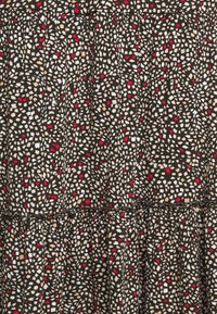 Tela negra con un patrón disperso de formas blancas, rojas y beige. Presenta una cintura fruncida con un borde decorativo.