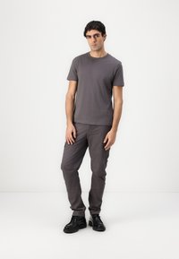 Graues Baumwoll-T-Shirt und passende Cargo-Hosen, die eine lockere Passform bieten. Schwarze Schuhe runden das Outfit ab. Einfaches, minimalistisches Design.