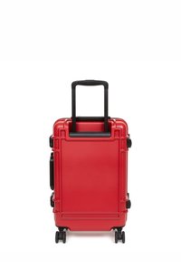 Red hard-shell suitcase with black pull handle and wheels, featuring a smooth texture and rectangular shape, equipped with side handles.