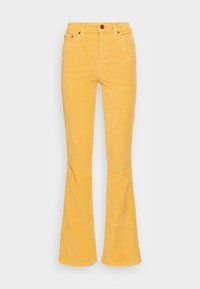 Calças de veludo cotelê amarelas, skinny na cintura, com design clássico de cinco bolsos e um único botão na frente. A textura é estriada.