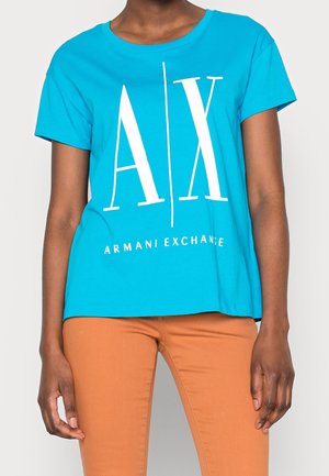 Camiseta de algodón color turquesa con un gran logo blanco "AX" y el texto "ARMANI EXCHANGE". Mangas cortas y un corte relajado.