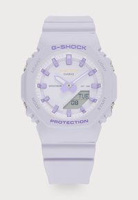 Lilla G-Shock klokke med matt finish, digital og analog visning, gummistropp og sølvdetaljer. Vanntett opptil 20 bar.