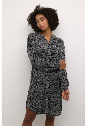 Robe à manches longues bleu marine avec un tissu texturé et à motifs. Elle présente un col en V et des boutons, une taille cintrée et des fentes sur les côtés.