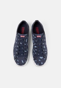Granatowe sneakersy sznurowane z jasnoniebieskim abstrakcyjnym wzorem i białymi podeszwami, z czerwonym logo Camper na języku i wkładkach, widok z góry.