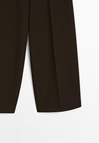 Partie inférieure d'un pantalon noir sur mesure à jambes droites sur fond blanc.