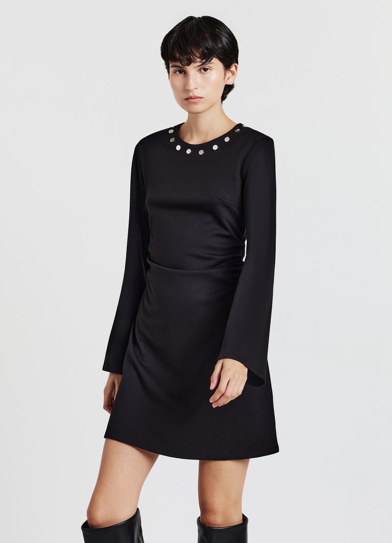 Schwarzes langärmliges Kleid mit rundem Ausschnitt und kreisförmigen Verzierungen, figurbetontem Schnitt und glatter Stoffstruktur.