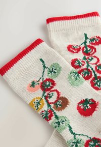 Knitted socks in cream color with red ribbed cuffs featuring an embroidered tomato pattern in various colors and green vines.