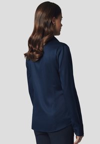 Granatowa, długorękawowa koszula, gładki materiał, dopasowany krój, wywinięty kołnierzyk, detal guzika na mankietach oraz lekko zaokrąglony dół.
