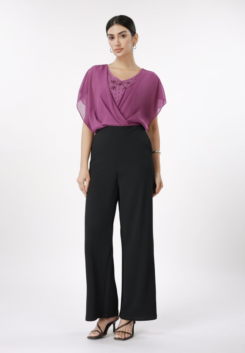 Gjennomsiktig lilla bluse med dekorative paljetter, kombinert med høytlivs svarte vidbente bukser og svarte sandaler med stropper.