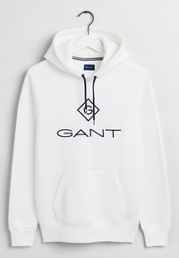 Sudadera blanca con bolsillo canguro, cordones azul marino y un logo bordado negro que dice "GANT" en la parte frontal. Textura de tela suave.