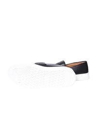 Scarpa nera slip-on con esterno in pelle liscia, suola in gomma bianca a contrasto con un motivo di presa testurizzato, caratterizzata da dettagli hardware minimi.