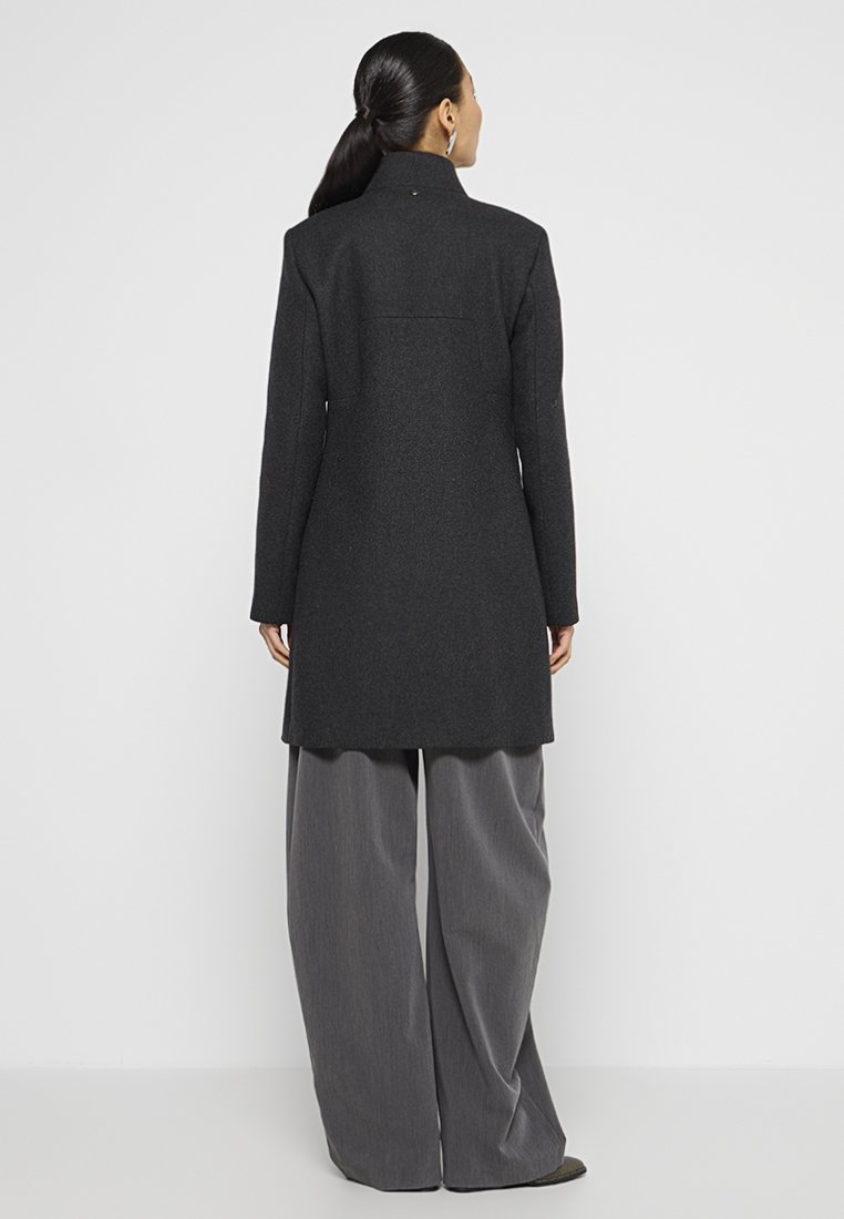 Cappotto lungo grigio scuro in lana con colletto alto, design su misura e silhouette dritta. Presenta una cucitura centrale sul retro e dettagli di cucitura delicati.