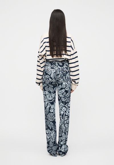 Ριγέ πουλόβερ σε μπεζ με ναυτικό μπλε; παντελόνι με υψηλή μέση σε ναυτικό μπλε με λευκό αφηρημένο κείμενο και σχέδια; άνετη εφαρμογή, λεία υφή.