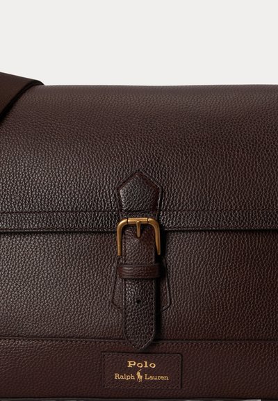 Σκούρα καφέ υφασμάτινη δερμάτινη τσάντα με χρυσό κούμπωμα και το λογότυπο Polo Ralph Lauren σε χρυσά γράμματα μπροστά.