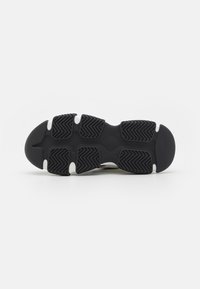 Black rubber shoe sole with textured traction pattern and white accents. Contoured design for flexibility and grip.