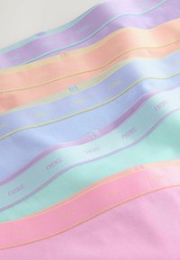 Naskladané pásy látok v pastelových farbách s malým textom "ďalej" opakujúcim sa na okraji každého pásu.