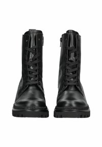 Une paire de bottes en cuir noir à lacets avec des semelles épaisses et des fermetures éclair latérales, vues de face sur un fond blanc.