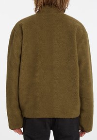 Olivgrön fleecejacka med mjuk och strukturerad yta, hög krage och lös passform, lämplig för vardagsbruk.