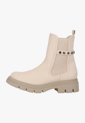 Botines beige hechos de material suave con paneles laterales elásticos y tachuelas de metal decorativas, que cuentan con una suela de goma texturizada y resistente.
