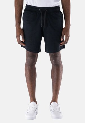 Shorts neri in cotone con vita elastica e cordoncino, dotati di tasche laterali e design a gamba dritta. Indossati con sneakers bianche.