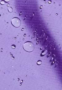 Tela morada con una superficie texturizada, decorada con gotas de agua, destacando su calidad resistente al agua.