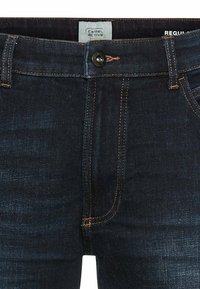 Donkerblauwe denim jeans met contrasterende oranje stiksels, een knoopsluiting, vijfzakkenontwerp en een label met de tekst "Camel Active."