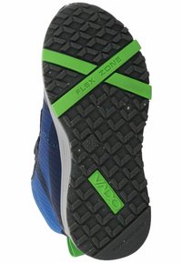 Suela de zapato con una base de goma negra que presenta un patrón texturizado y antideslizante, y un acento verde "ZONA FLEXIBLE". Lado de tela azul con rayas.