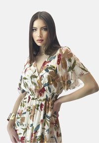 Robe florale avec des manches courtes et transparentes ; présente une taille cintrée et un mélange d'accents roses, verts et dorés sur un fond blanc.