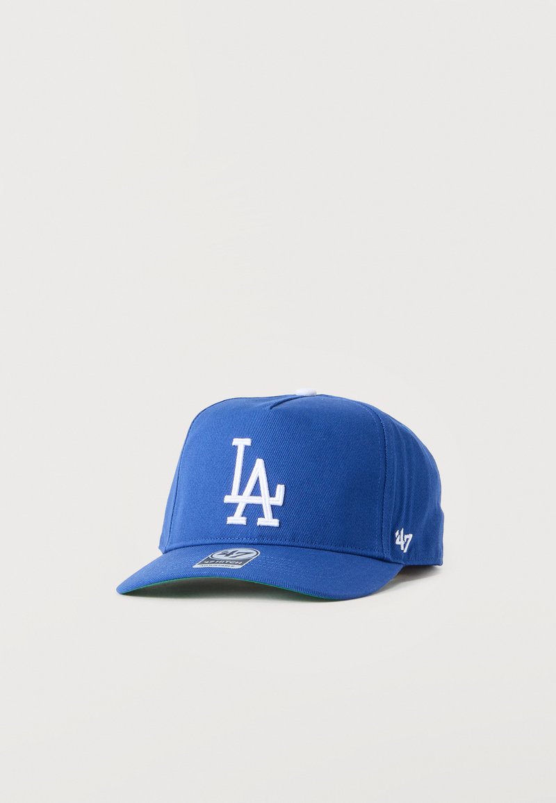 Blå baseballcaps med hvit "LA"-logo brodert på fronten og '47 merke på siden, vist mot en ensfarget bakgrunn.