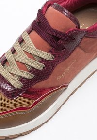 Baskets colorées avec cuir bordeaux et beige, imprimé serpent texturé, accents en mesh et lacets beiges. Semelle en caoutchouc blanche.