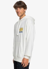 Sudadera blanca hecha de un tejido suave, con un bolsillo frontal, capucha con cordones y un gráfico de logo colorido en el pecho.
