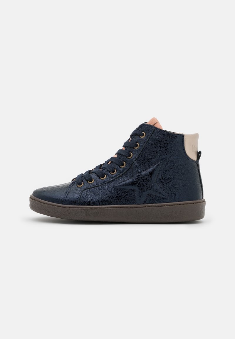 Baskets montantes bleu marine avec motif étoile, lacets noirs, col beige à la cheville et semelle marron sur fond gris clair.