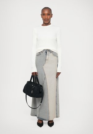 Gonna di jeans lunga con design a blocchi di colore in blu chiaro e scuro, abbinata a una camicia aderente bianca a maniche lunghe e una borsa nera.