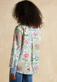 Floral-patterned shirt in light fabric with blue and pink designs. Features a blue striped cuff and a relaxed fit with a straight back.