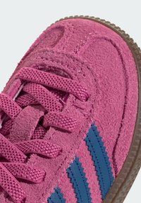 Rosa sneakers i mocka med blå syntetiska tre-randiga detaljer, strukturerade snören och en gummisula med distinkt mönster för grepp.