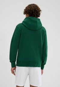Sudadera con capucha verde hecha de tela suave, con un bolsillo canguro y puños de canalé. Ajuste clásico con un diseño simple.
