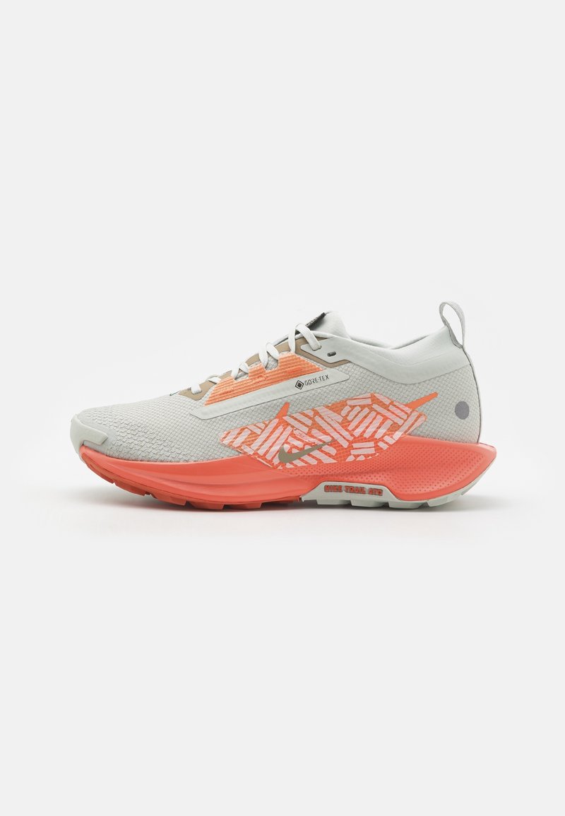 Chaussure de trail gris clair et corail avec étiquette GORE-TEX, détail latéral à motif et semelle coussinée conçue pour la durabilité en extérieur.