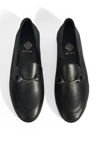 Schwarze Lederloafers mit abgerundeter Zehenform, die ein dekoratives Metallelement auf dem Rist und eine glatte, strukturierte Oberfläche aufweisen.