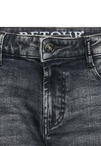 Ciemnoszare dżinsy o luźnym kroju, z metalowym zapięciem na guzik, przeszyciami w przednich kieszeniach oraz markową metką na pasku.